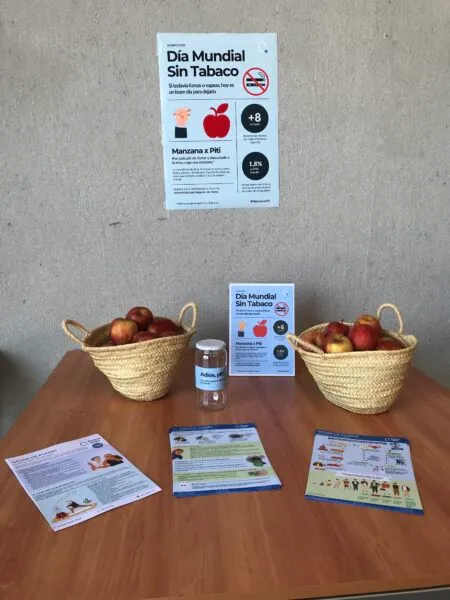 Material informativo del Día Mundial Sin Tabaco con folletos y manzanas en mesa de concienciación
